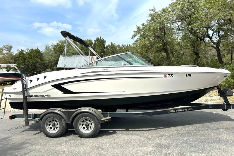 Slide: The Image of 2016 Chaparral 21 H2O Sport boat on trailer, parked outdoors with trees in background. - 6