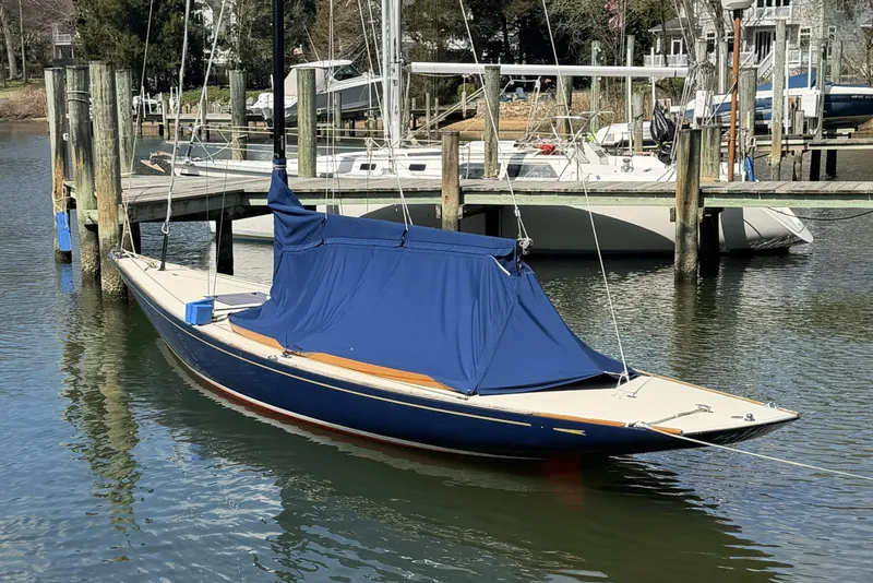 Slide: The Image of 2014 C.W. Hood 32 Daysailer docked, covered in blue tarp, in a serene marina setting. - 2