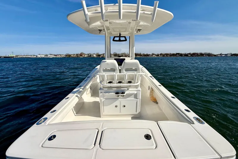 Slide: The Image of 2022 Regulator 23 boat on water, featuring spacious deck and seating under clear blue sky. - 10