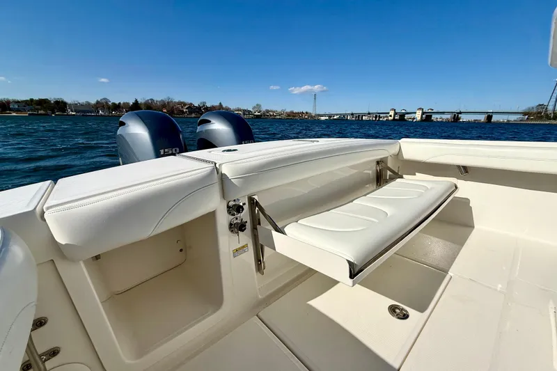 Slide: The Image of 2022 Regulator 23 boat with dual engines and foldable seating, on a sunny day by the water. - 14