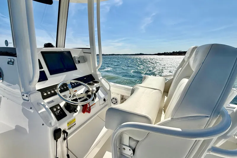 Slide: The Image of 2022 Regulator 23 boat interior with steering console, white seats, and ocean view. - 17
