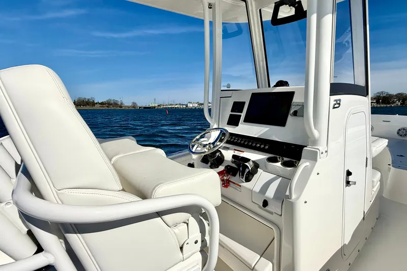 Slide: The Image of 2022 Regulator 23 boat cockpit with modern controls and white seating on open water. - 18