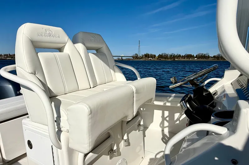 Slide: The Image of 2022 Regulator 23 boat with white seating and steering wheel on a sunny day. - 19