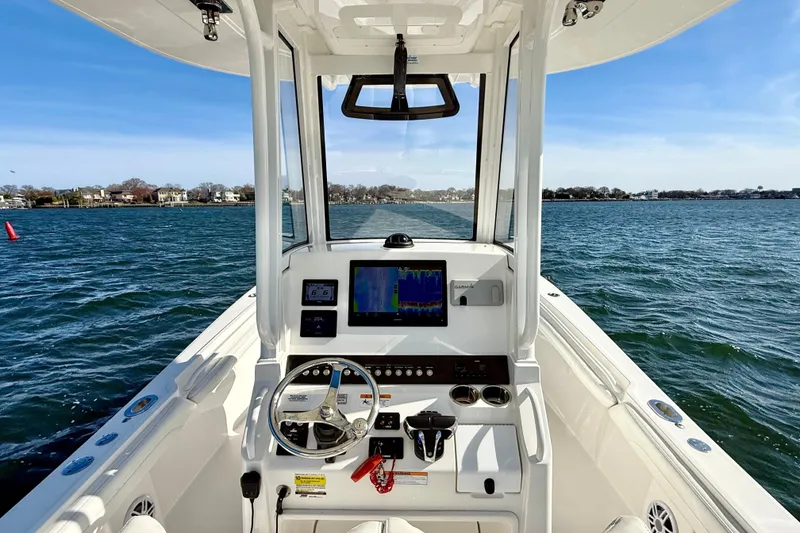 Slide: The Image of 2022 Regulator 23 boat cockpit with steering wheel and navigation display on open water. - 20