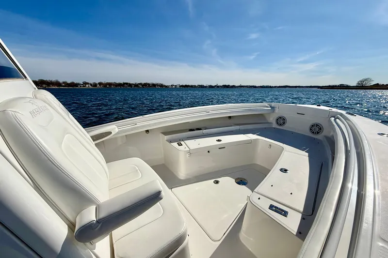 Slide: The Image of 2022 Regulator 23 boat interior with white seating, on calm water under blue sky. - 22