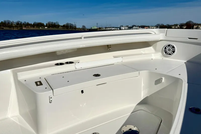 Slide: The Image of 2022 Regulator 23 boat interior with storage compartment and speaker, docked by the water. - 25