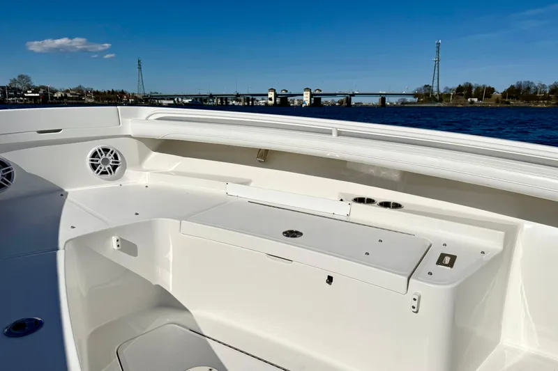 Slide: The Image of 2022 Regulator 23 boat interior with storage and speakers, on a sunny day by the water. - 26