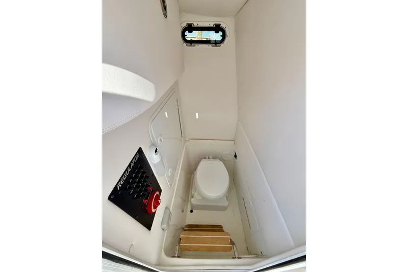 Slide: The Image of 2022 Regulator 23 boat interior with compact marine toilet and control panel. - 27