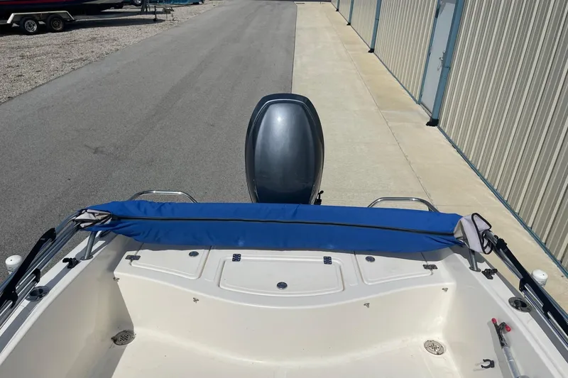 Slide: The Image of 2013 Pioneer 175 Venture boat with blue cover, parked near storage units. - 10