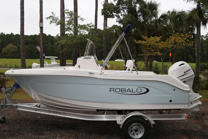 Slide: The Image of 2026 Robalo R180 Center Console boat on trailer, surrounded by trees. - 3
