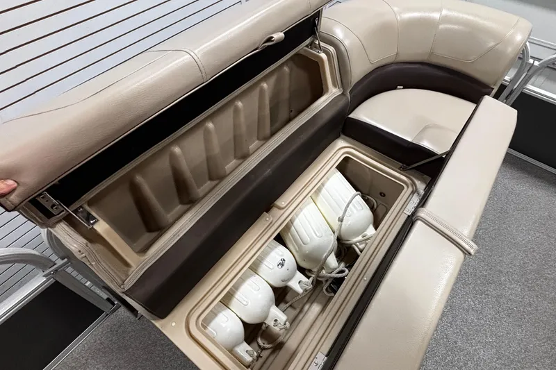 Slide: The Image of 2018 Sun Tracker Party Barge 20 DLX storage compartment with beige seating and boat accessories. - 8