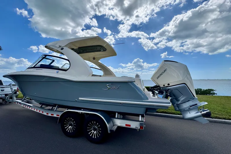 Slide: The Image of 2027 Scout 288 Dorado boat on trailer by the water under a cloudy sky. - 2
