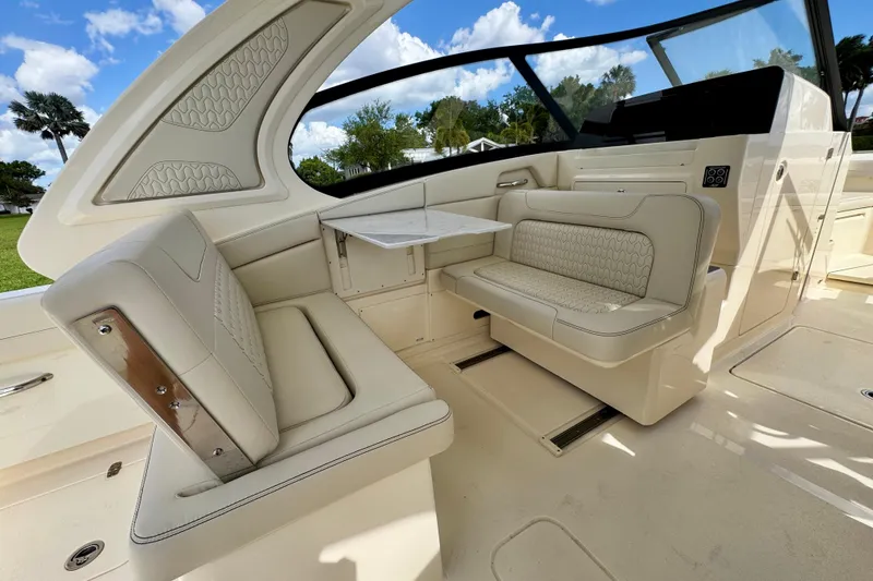 Slide: The Image of 2027 Scout 288 Dorado boat interior with luxurious seating and table, under a clear blue sky. - 23