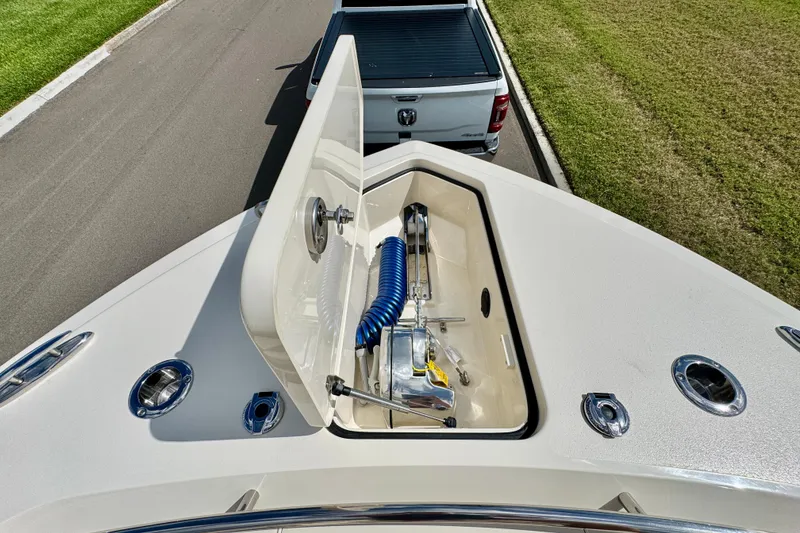 Slide: The Image of 2027 Scout 288 Dorado boat with open storage compartment, parked near a white truck. - 36