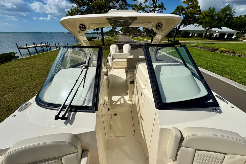 Slide: The Image of 2027 Scout 288 Dorado boat with open cockpit, docked by a scenic waterfront. - 38