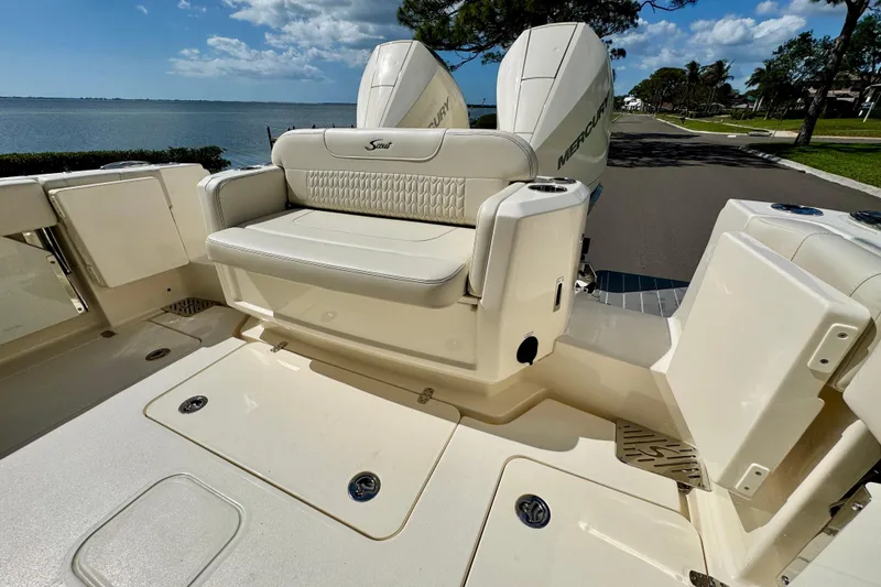Slide: The Image of 2027 Scout 288 Dorado boat with luxurious seating and dual Mercury engines, docked by the water. - 6