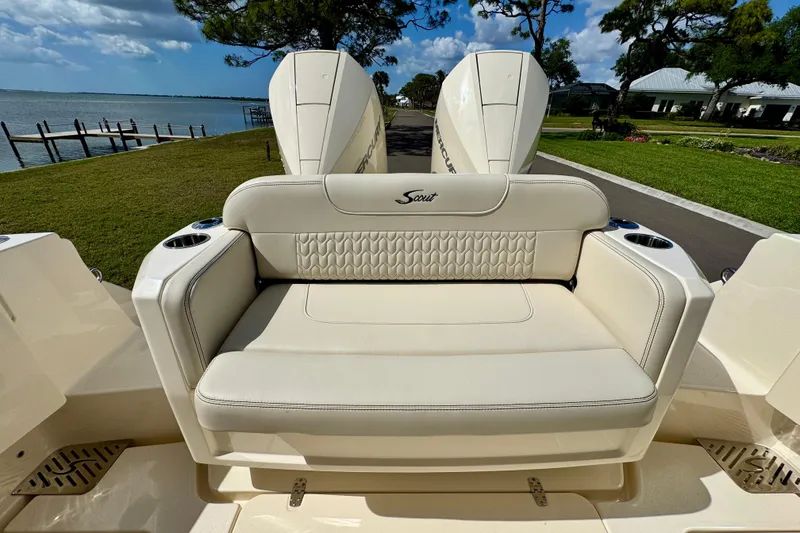 Slide: The Image of 2027 Scout 288 Dorado boat with luxurious seating, docked by a scenic waterfront. - 7