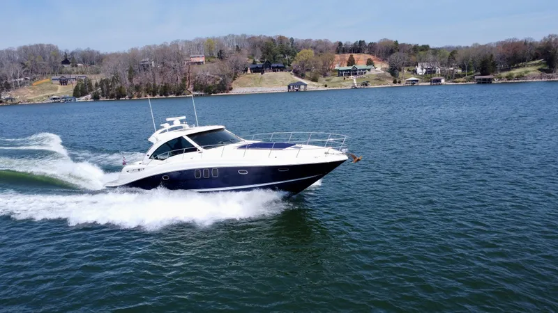 Slide: The Image of 2006 Sea Ray 48 Sundancer cruising on a scenic lake with shoreline in the background. - 12
