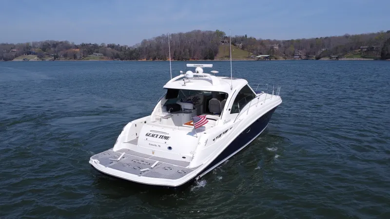 Slide: The Image of 2006 Sea Ray 48 Sundancer yacht cruising on a serene lake with scenic background. - 7