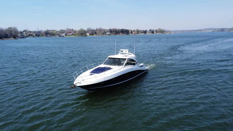 Slide: The Image of 2006 Sea Ray 48 Sundancer yacht cruising on a serene lake. - 9