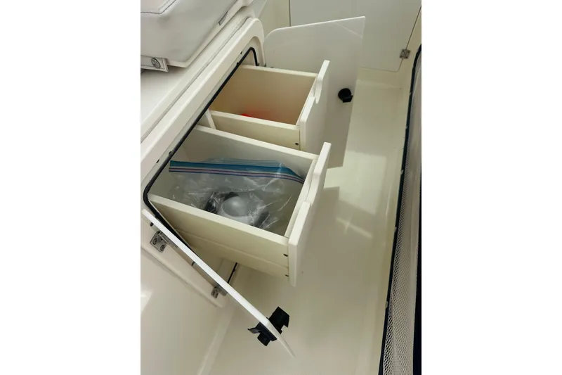 Slide: The Image of 2007 Pursuit 235 Denali LS boat storage drawers with open compartments. - 10
