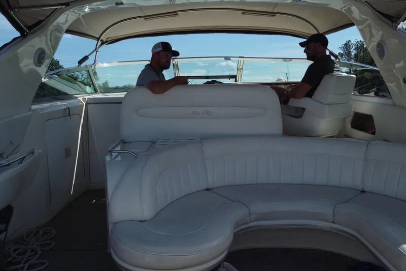 Slide: The Image of Interior of a 1997 Sea Ray 450 Sundancer with two people seated, featuring white leather seating. - 17
