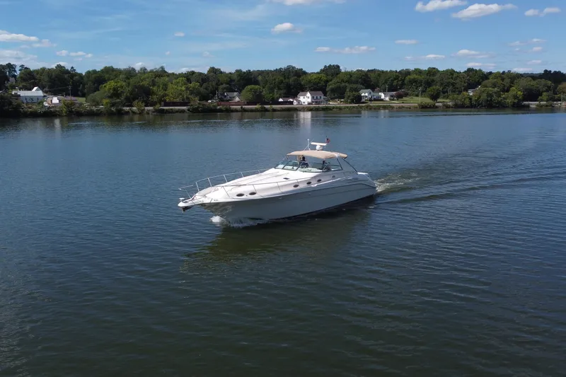 Slide: The Image of 1997 Sea Ray 450 Sundancer cruising on a calm lake under a clear blue sky. - 27