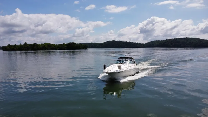 Slide: The Image of Sea Ray 410 Sundancer 2000 cruising on a serene lake under a partly cloudy sky. - 1