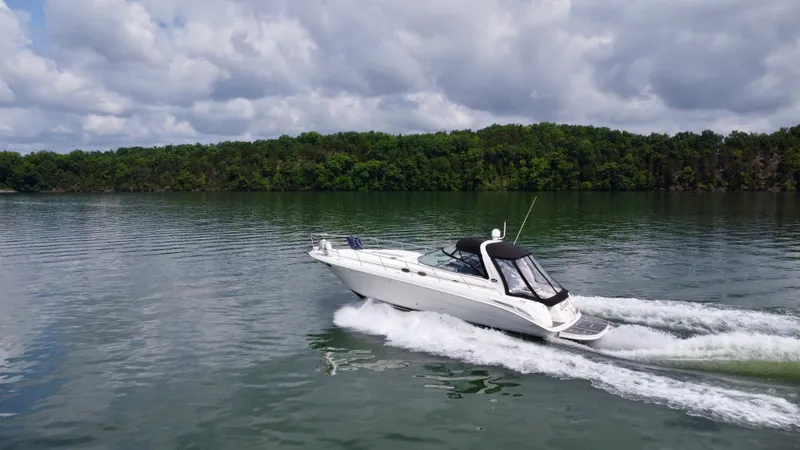 Slide: The Image of Sea Ray 410 Sundancer 2000 cruising on a serene lake with lush green shoreline. - 2