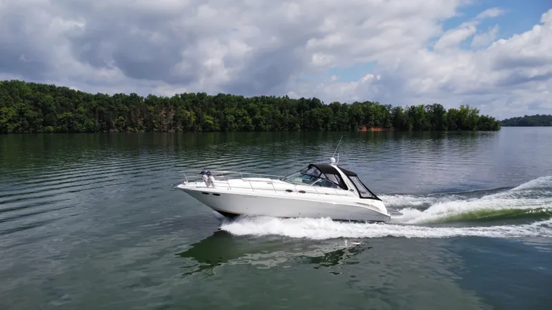 Slide: The Image of 2000 Sea Ray 410 Sundancer cruising on a serene lake under a partly cloudy sky. - 49