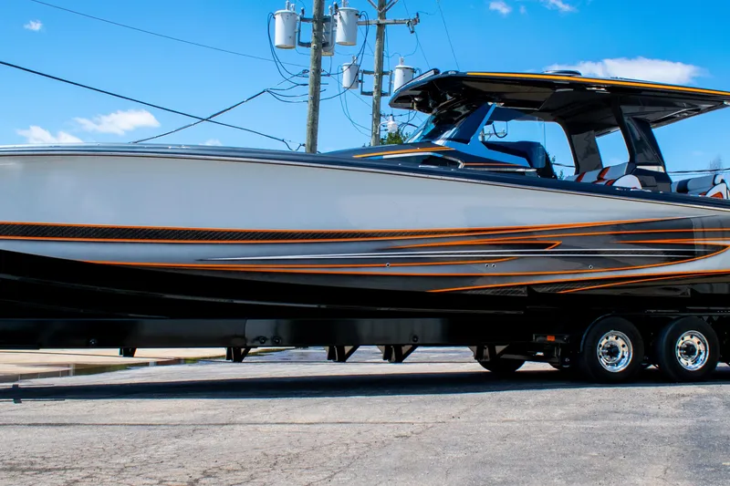 Slide: The Image of 2027 Nor-Tech 450 Sport Center Console boat on trailer, sleek design with orange accents. - 3