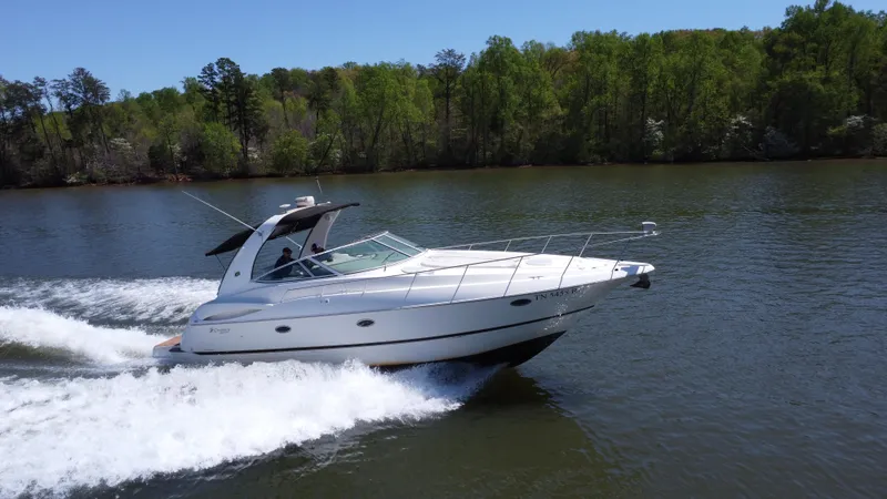 Slide: The Image of 2004 Cruisers Yachts 370 Express speeding on a lake with lush green trees. - 1