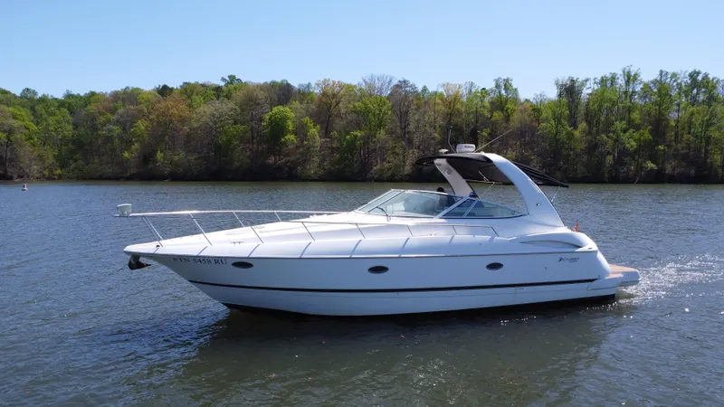 Slide: The Image of 2004 Cruisers Yachts 370 Express on a serene lake with lush green trees. - 13
