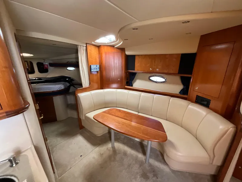 Slide: The Image of 2004 Cruisers Yachts 370 Express interior with curved seating and wooden table. - 18