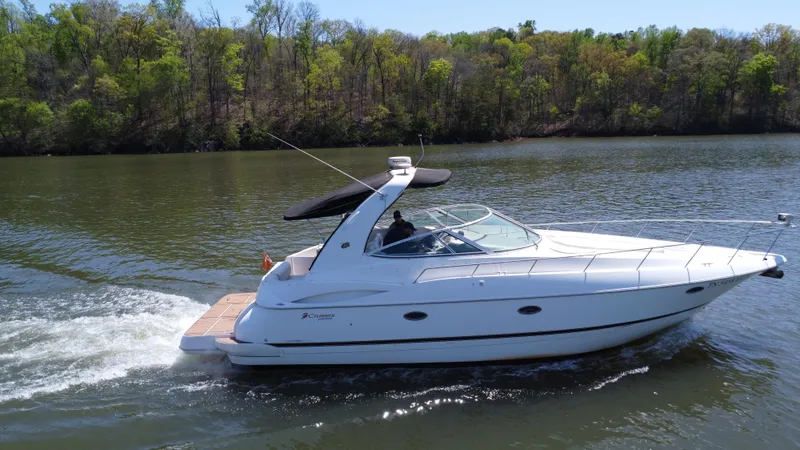 Slide: The Image of 2004 Cruisers Yachts 370 Express cruising on a serene lake with lush green shoreline. - 2