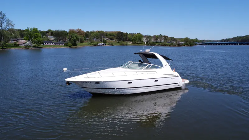 Slide: The Image of 2004 Cruisers Yachts 370 Express on a serene lake with lush green shoreline. - 7