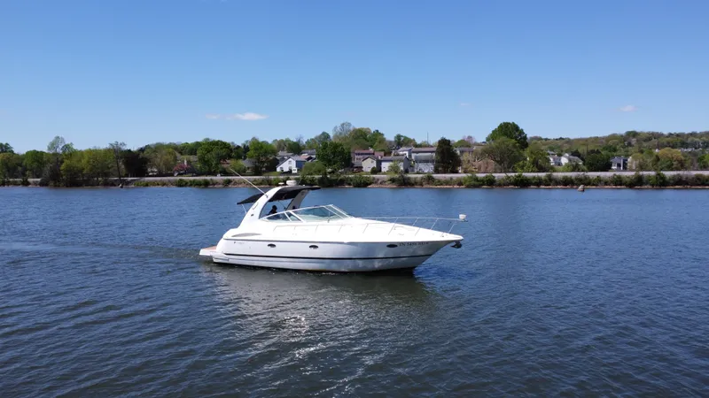 Slide: The Image of 2004 Cruisers Yachts 370 Express on calm water with scenic shoreline background. - 9