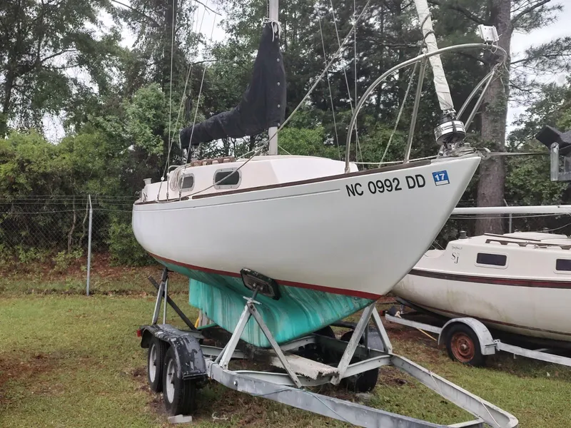 The Image of 1979 Alberg 22 sailboat on trailer, parked on grass near trees. - 0