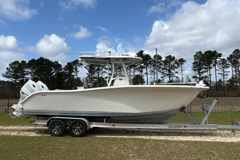 The Image of 2021 Sea Pro 259 DLX boat on trailer, parked outdoors under a cloudy sky. - 1