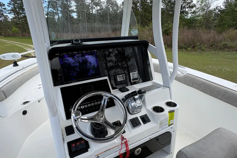 Slide: The Image of 2021 Sea Pro 259 DLX boat dashboard with steering wheel and navigation controls. - 10