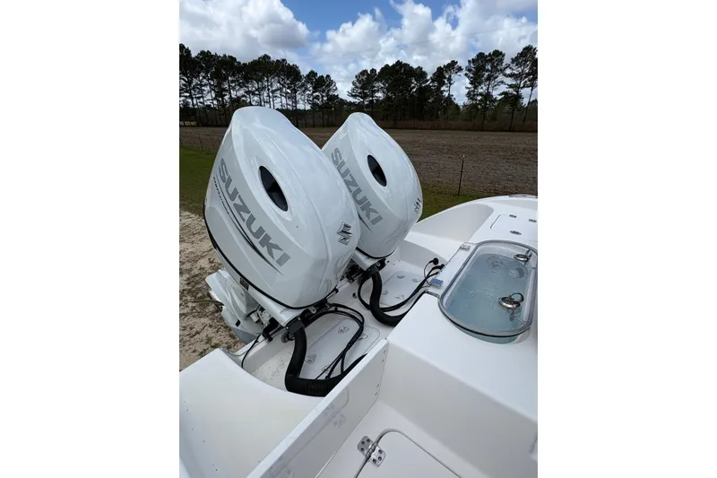 Slide: The Image of Twin Suzuki outboard engines on a 2021 Sea Pro 259 DLX boat under a cloudy sky. - 17