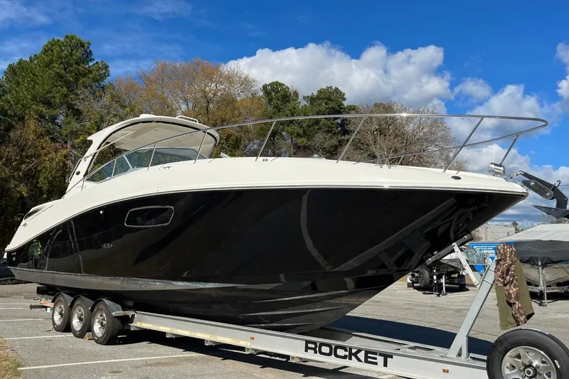 The Image of 2010 Sea Ray 370 Express Cruiser on trailer, parked outdoors under blue sky. - 1