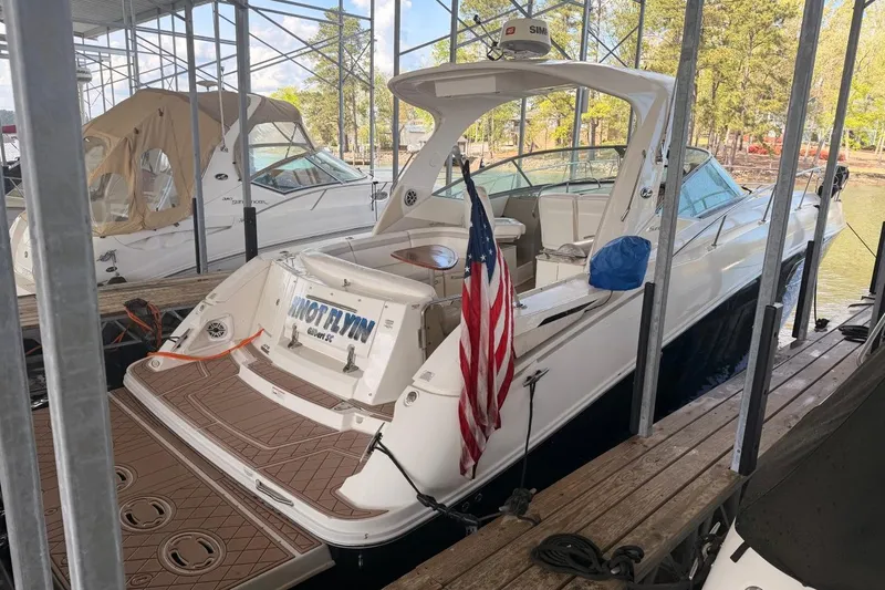Slide: The Image of 2010 Sea Ray 370 Express Cruiser docked with American flag, surrounded by trees. - 6