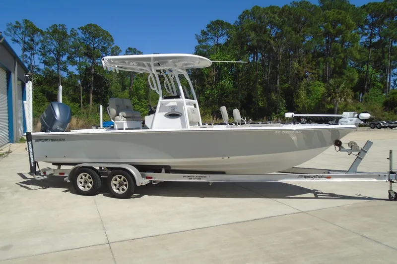 The Image of 2021 Sportsman Masters 247 Bay Boat on trailer, parked outdoors, surrounded by trees. - 1
