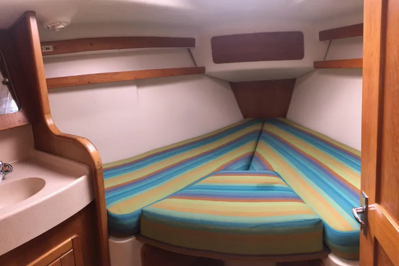 Slide: The Image of Cozy cabin interior of a 1998 Catalina 380 sailboat with colorful striped bedding. - 8