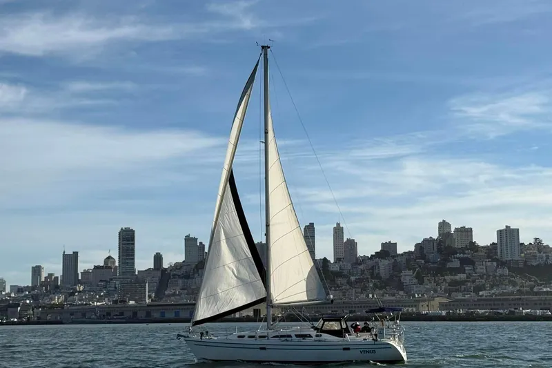 Slide: The Image of Sailboat Catalina 380, 1998 model, cruising near a city skyline under a clear sky. - 21