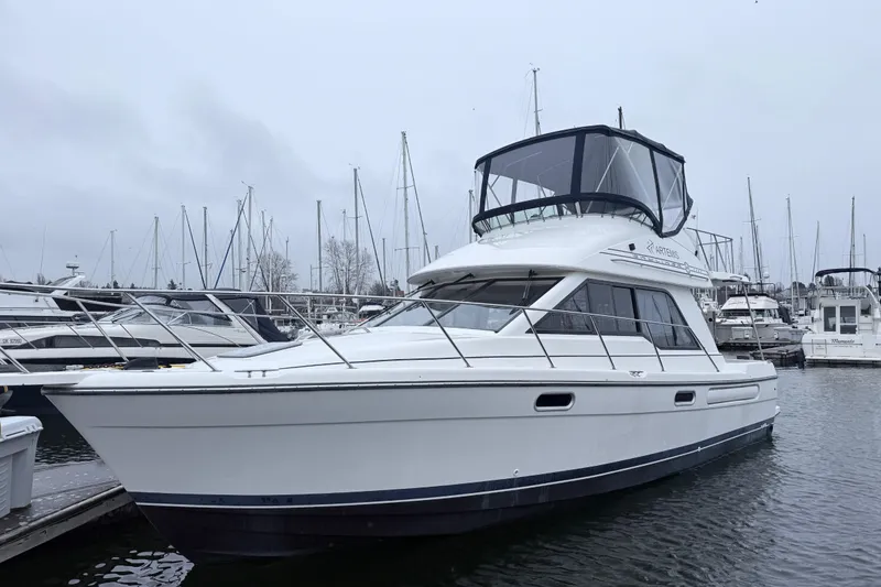 Slide: The Image of 2000 Bayliner 3388 Command Bridge Motoryacht docked in a marina, surrounded by sailboats. - 3