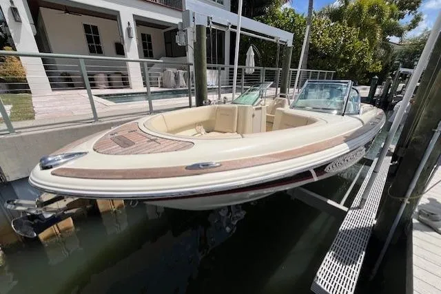 The Image of 2019 Chris-Craft Launch 27 boat docked near a modern waterfront home. - 1