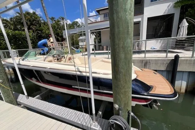 Slide: The Image of 2019 Chris-Craft Launch 27 boat docked on a lift in a scenic canal setting. - 2
