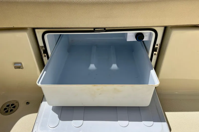 Slide: The Image of Open storage compartment on 2019 Chris-Craft Launch 27 boat, featuring a white pull-out tray. - 32